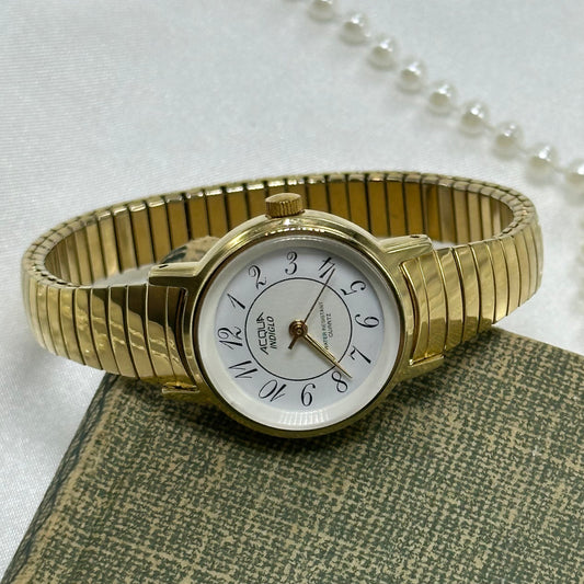 Simple classic gold tone watch with round dial and stretchable band.