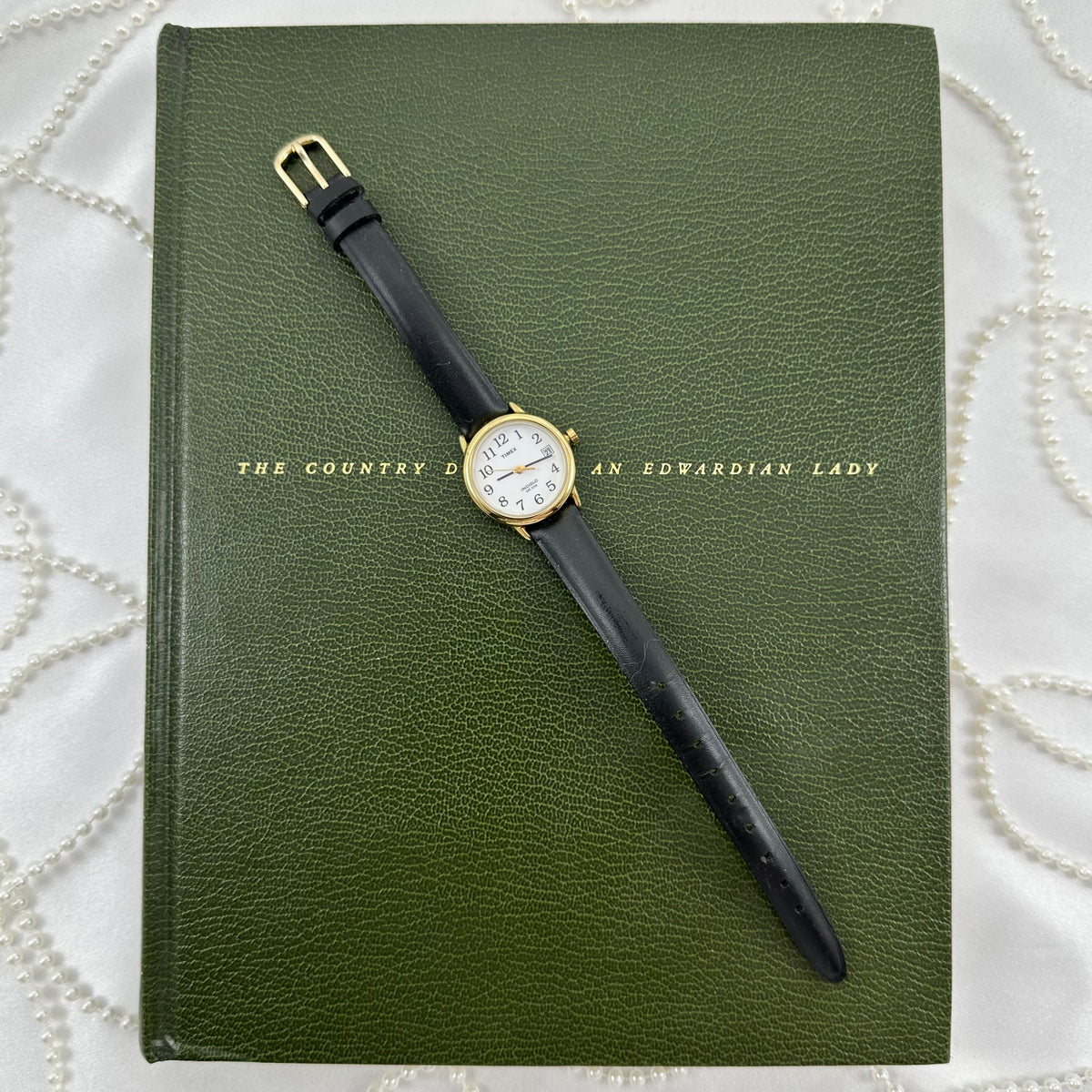 Classic gold tone Timex Indiglo round dial watch with date display and black leather band. Water resistant 10M.