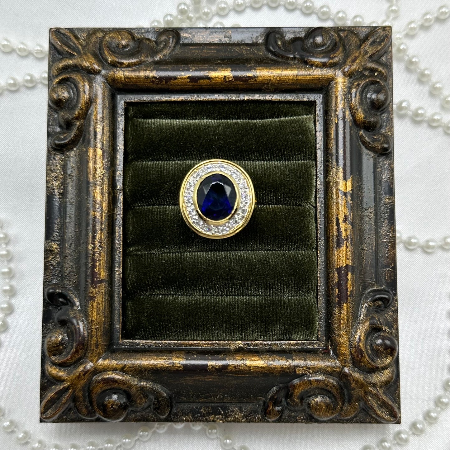 14k gold electroplated vintage deadstock ring with large dark blue cubic zirconia stone surrounded by clear cubic zirconia stones.