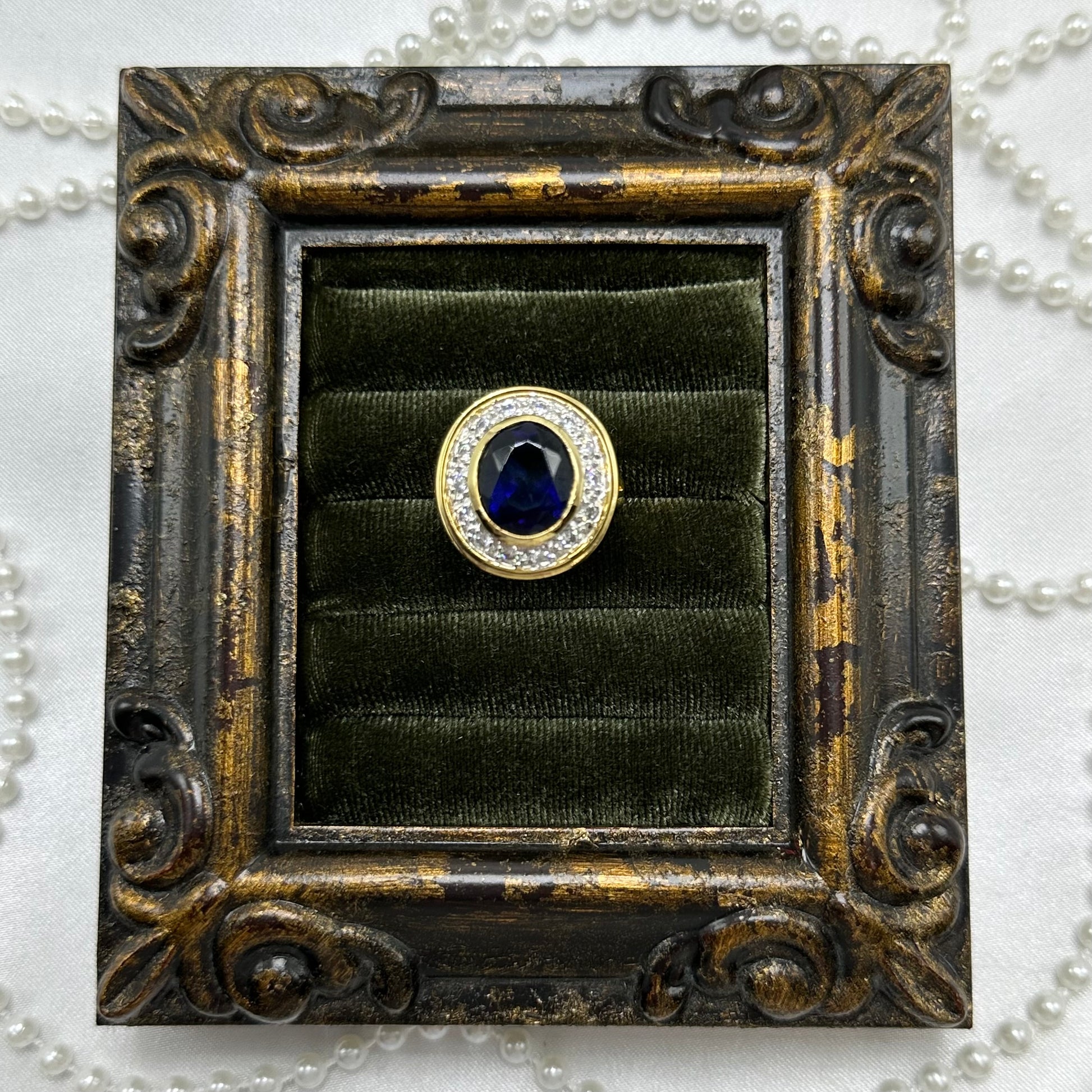 14k gold electroplated vintage deadstock ring with large dark blue cubic zirconia stone surrounded by clear cubic zirconia stones.