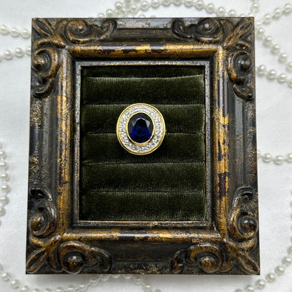 14k gold electroplated vintage deadstock ring with large dark blue cubic zirconia stone surrounded by clear cubic zirconia stones.