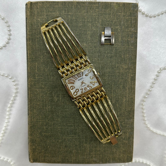 Gold tone chunky cuff watch with quartz movement and mother of pearl dial.