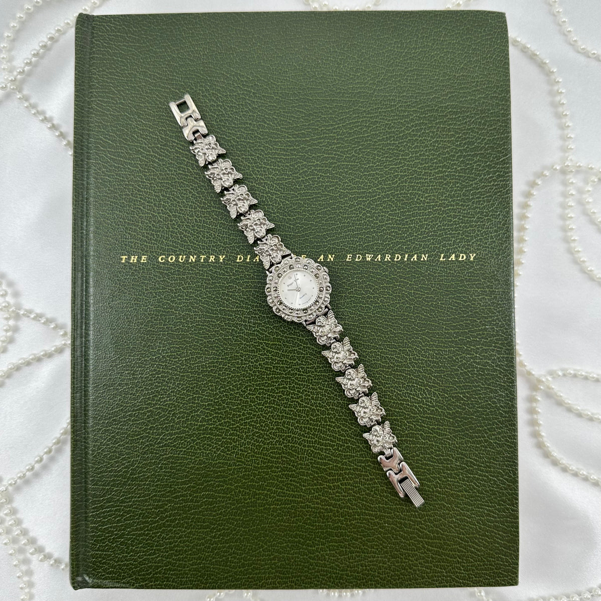 Vintage silver tone watch with round dial and angel charm band.