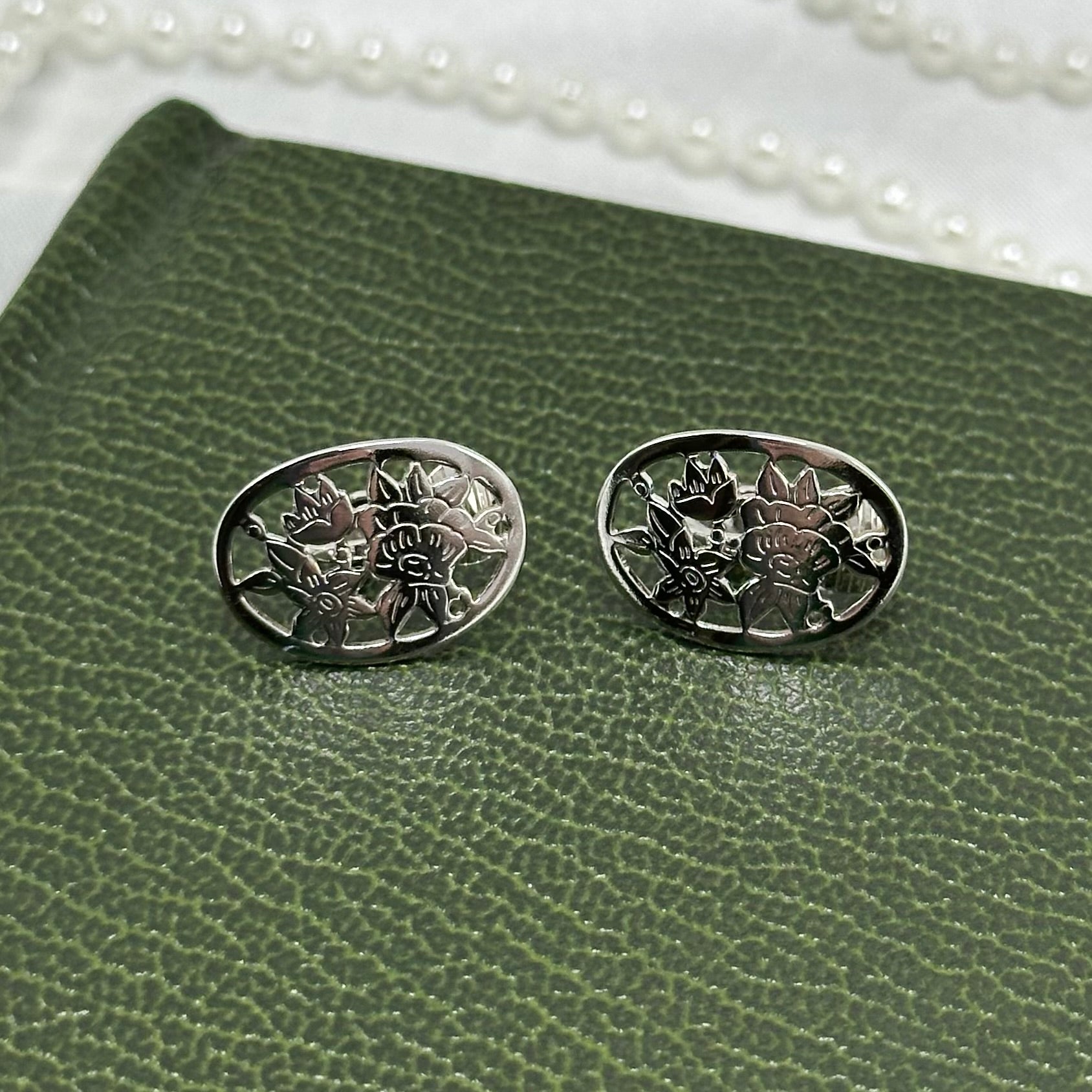 Rare vintage silver tone oval Avon clip on earrings with intricate flower cut out from the 1980's.