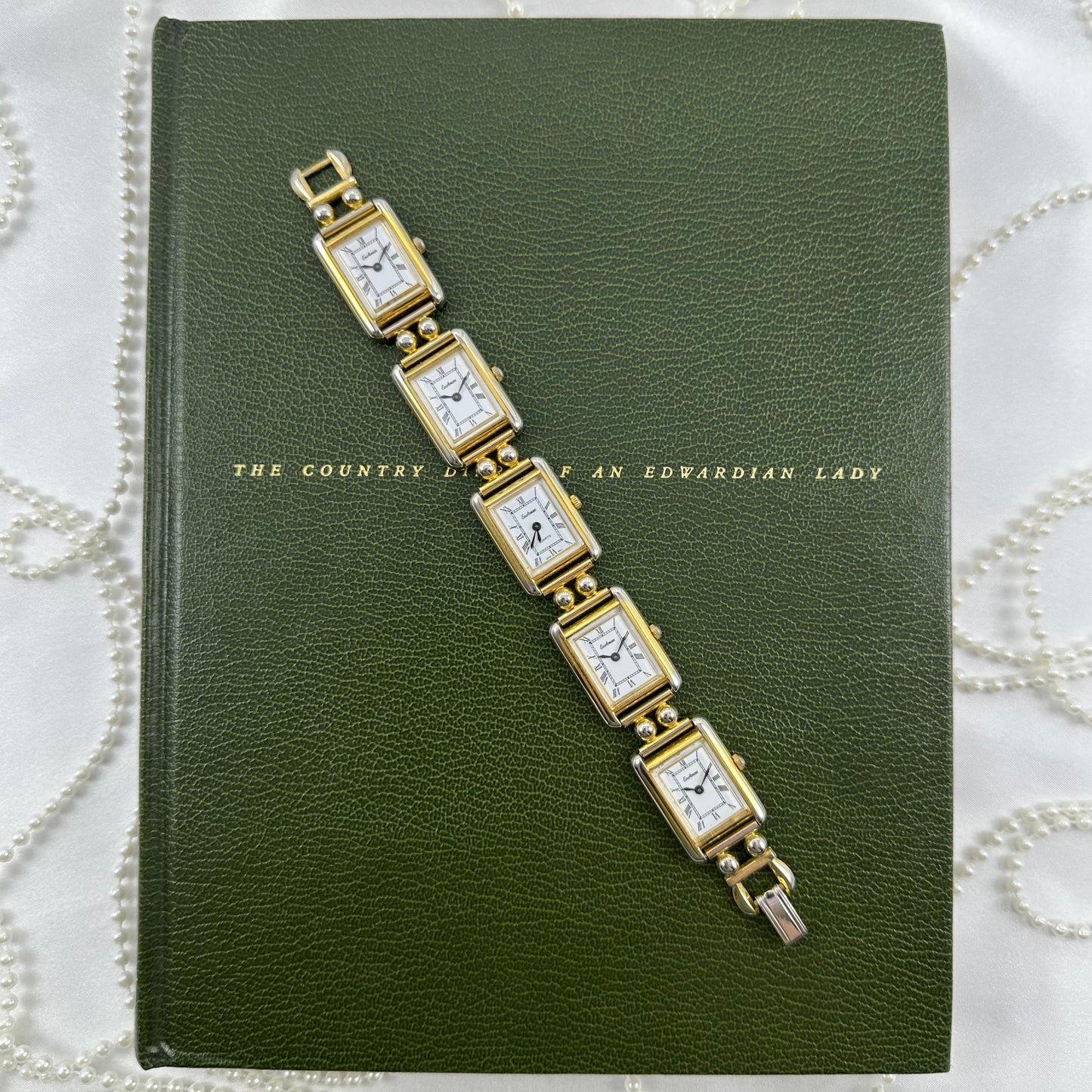 Vintage gold tone multi face watch with 5 rectangular dials and black jewel crown. Middle dial is functional.