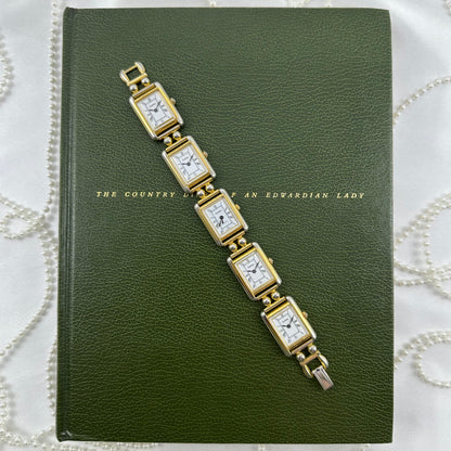 Vintage gold tone multi face watch with 5 rectangular dials and black jewel crown. Middle dial is functional.