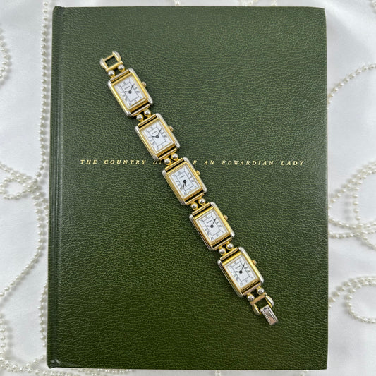 Vintage gold tone multi face watch with 5 rectangular dials and black jewel crown. Middle dial is functional.