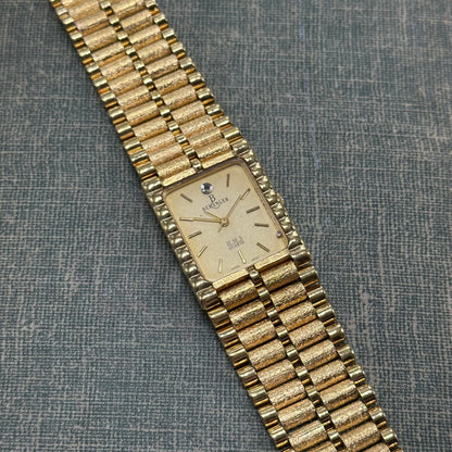 Vintage gold tone chunky tank Berenger watch with rectangle dial and textured clasp band.