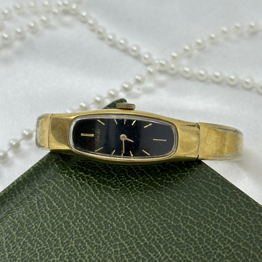 Vintage gold tone Seiko manual winding watch with bangle style band and black oval dial from the 1980's.