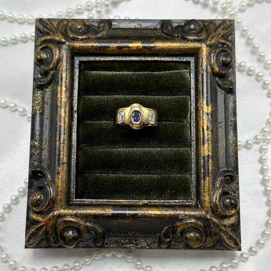 14k gold electroplated vintage deadstock ring with oval purple stone surrounded by two rectangular clear cubic zirconia stones.