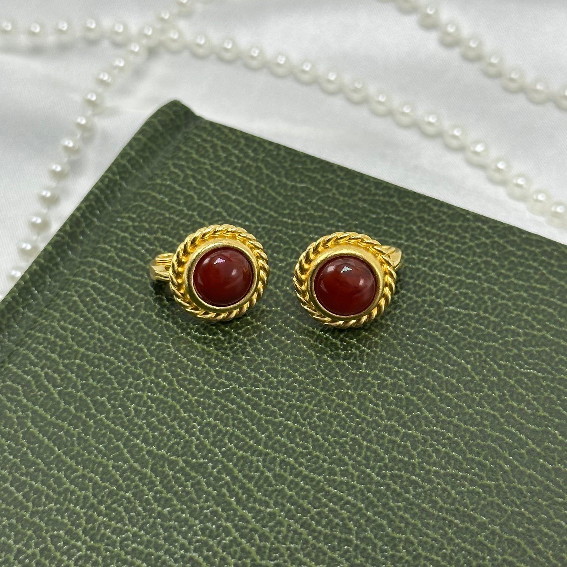 Adorable vintage oval clip on earrings with red stones and braided metal rope frames.