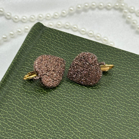 Gold tone clip on earrings with dark purple glitter leaves.