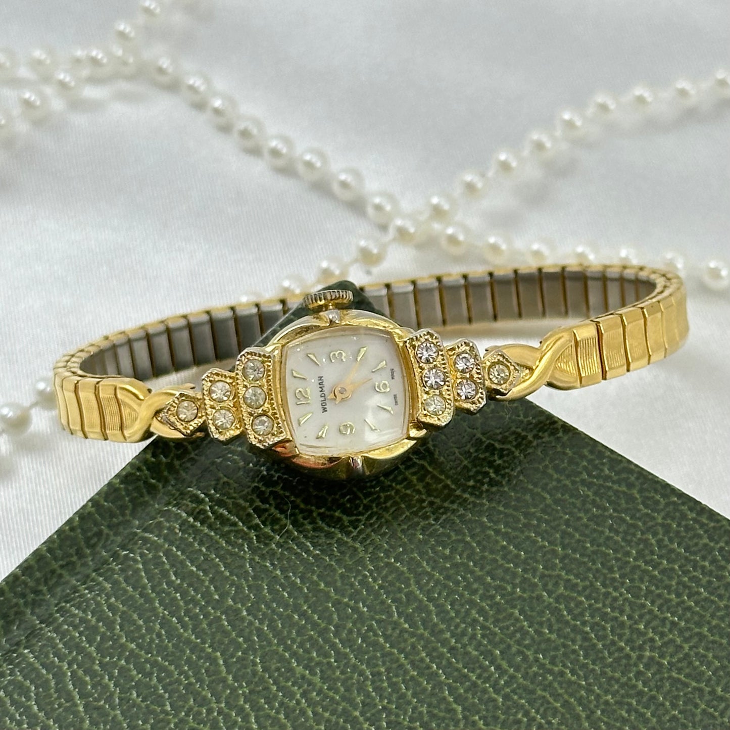 Vintage art deco gold tone Woldman watch with rhinestone accent case and stretchable band.