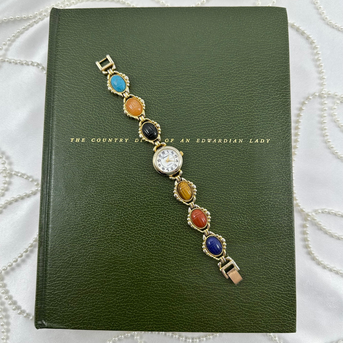 Vintage gold tone multicolor scarab watch with mother of pearl dial and quartz movement.
