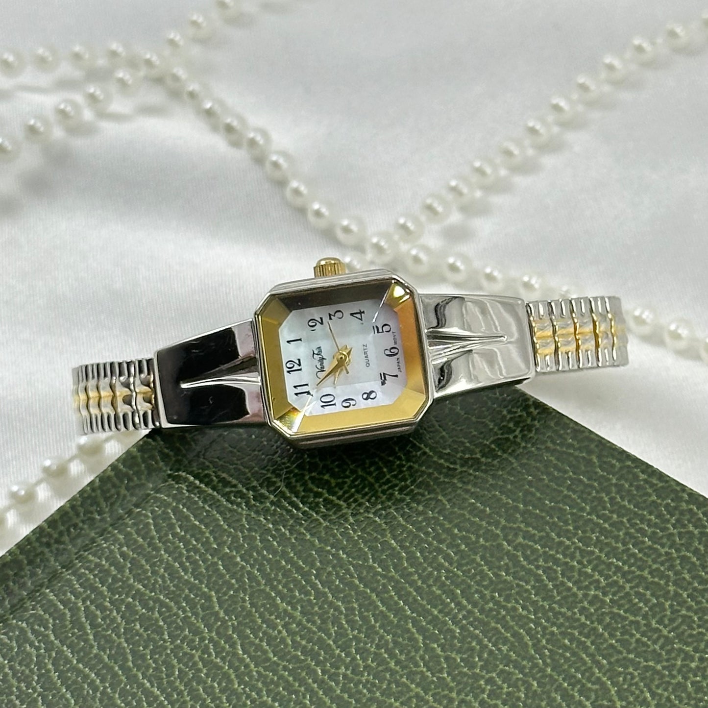 Vintage silver and gold tone Vanity Fair watch with square dial and stretchable two-tone band.