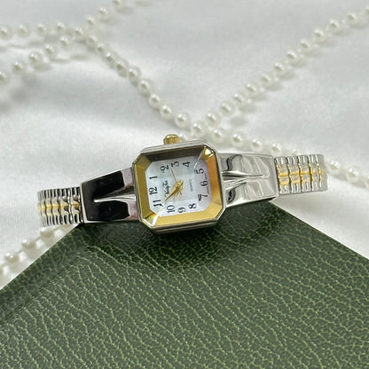 Vintage silver and gold tone Vanity Fair watch with square dial and stretchable two-tone band.