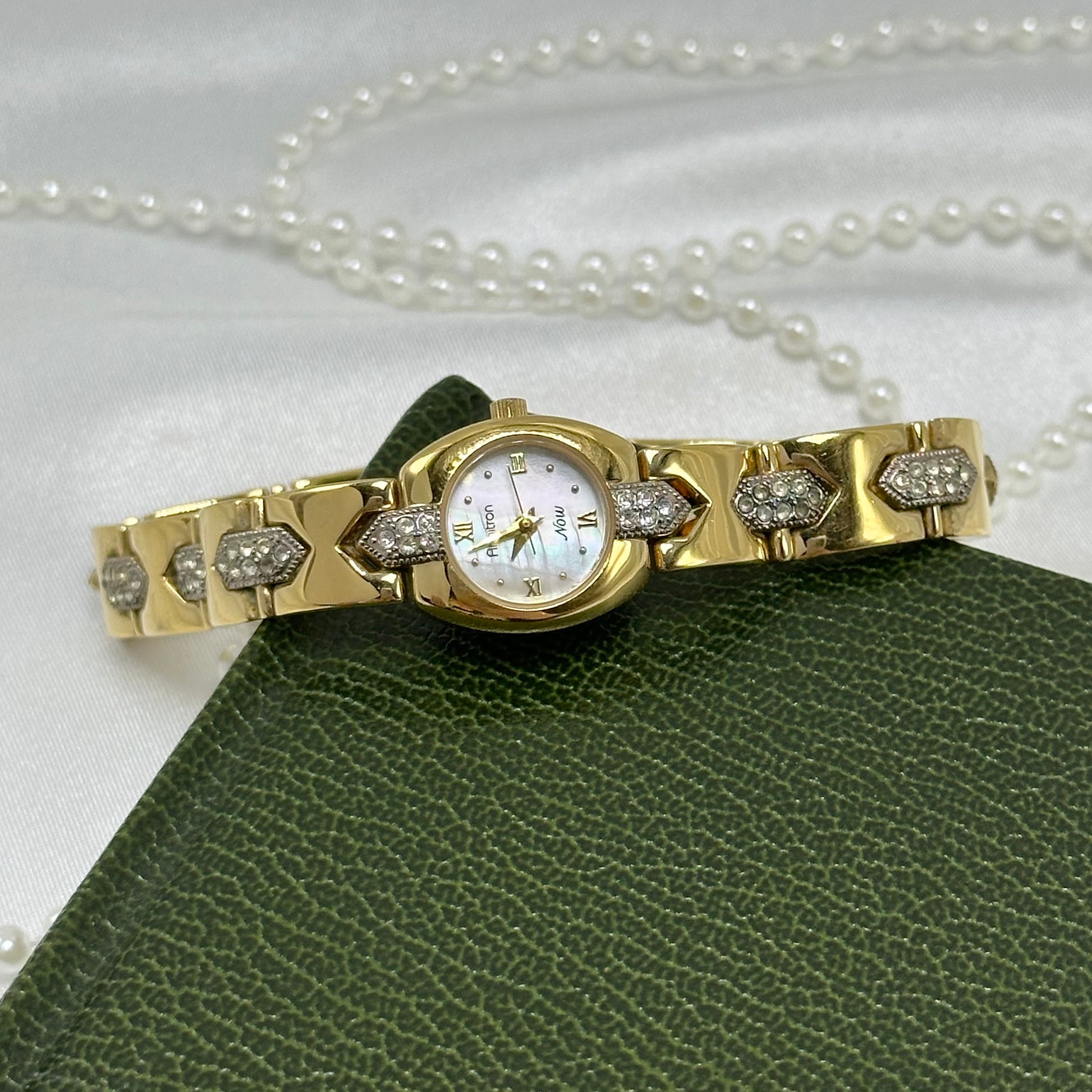 Vintage gold and silver tone Armitron watch with mother of pearl dial, roman numeral markers and diamanté bracelet band.