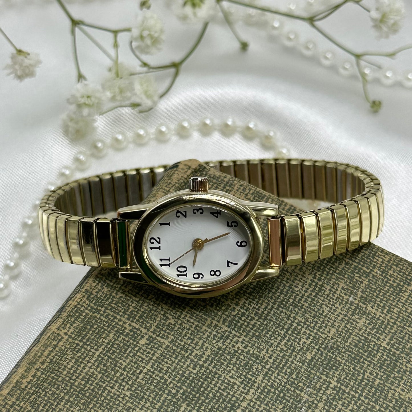 Classic oval dial gold tone watch with stretchable band.