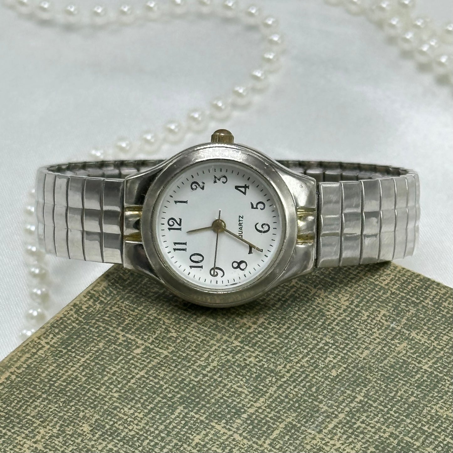 Classic silver tone round dial watch with stretchable band and quartz movement.