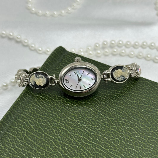 Vintage silver tone watch with black cameos, crystal stones, and mother of pearl dial.