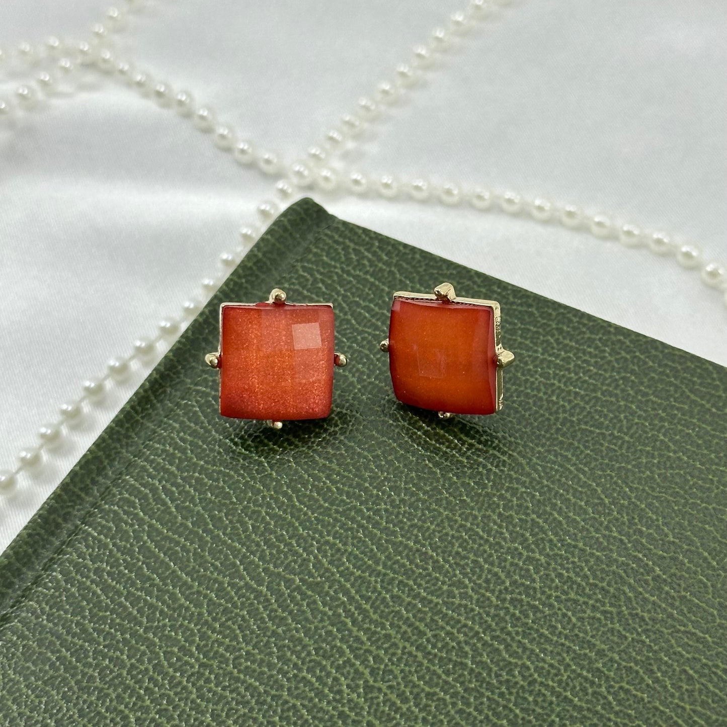 Vintage stud earrings with square, orange/red faceted stones set in a gold tone frame.