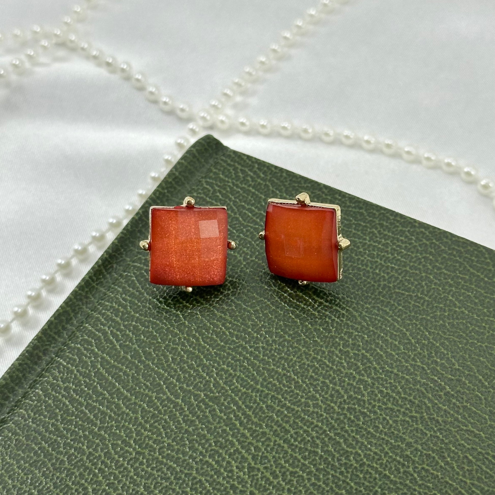 Vintage stud earrings with square, orange/red faceted stones set in a gold tone frame.