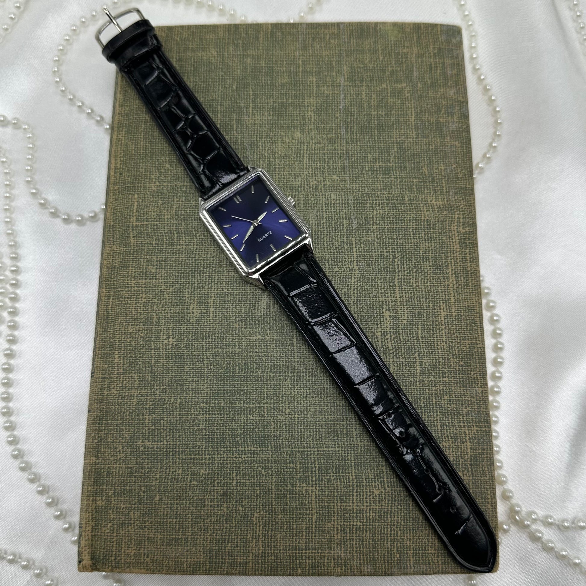 Silver tone watch with dark blue dial and black leather band.