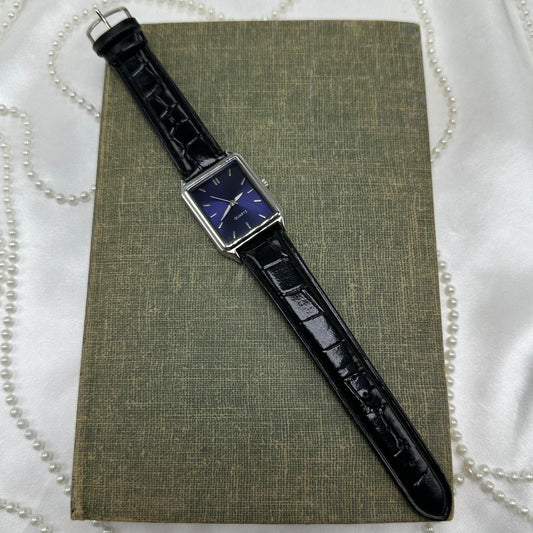 Silver tone watch with dark blue dial and black leather band.