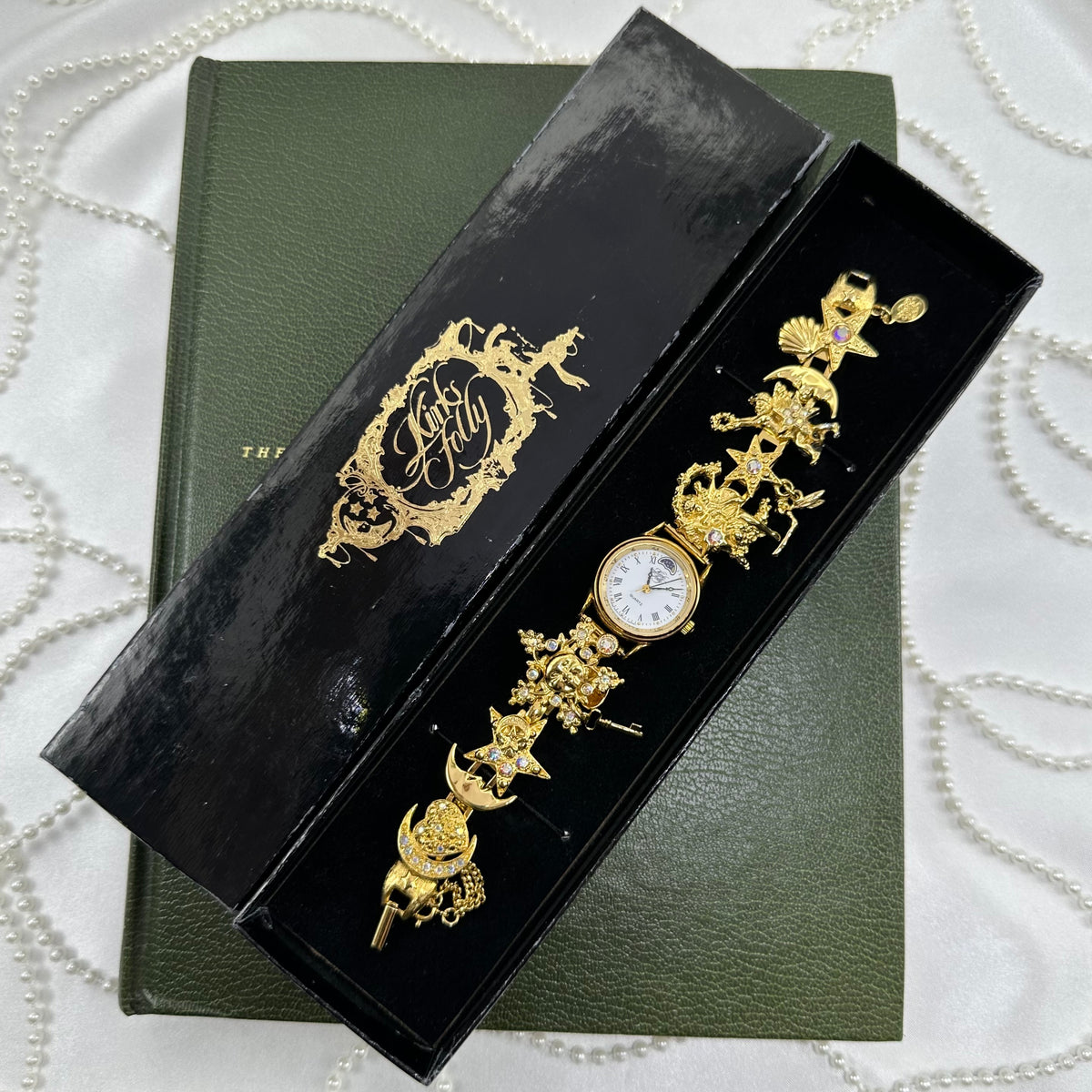 Vintage gold tone rare Kirks Folly charm watch covered in aurora borealis stones with celestial and fantasy charms like moons, stars, and fairies. Comes with original box.