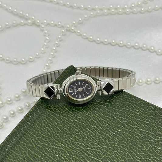 Dainty silver tone Rumours watch with black oval dial and black diamond stretchable band.