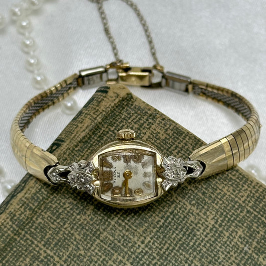 Dainty vintage 10k rolled gold plated Bulova 23 jewels manual winding cocktail watch from the 1960's with ornate diamanté dial and detailed clasp band.