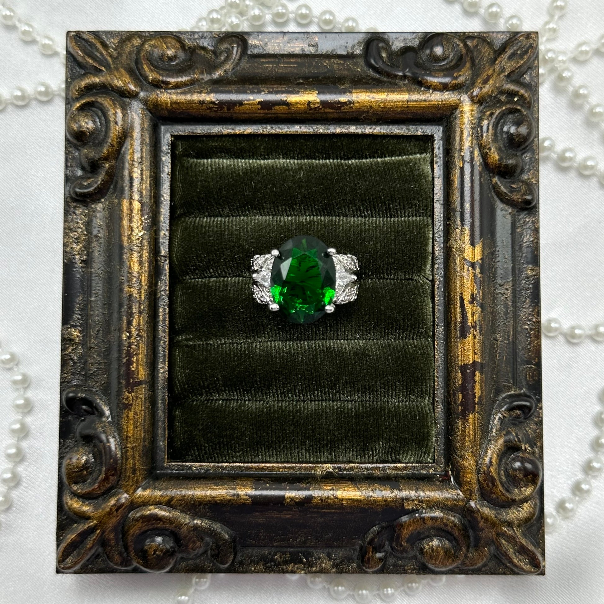 Rhodium plated vintage deadstock ring with large green center stone surrounded by clear cubic zirconia stones.