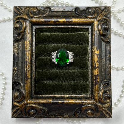 Rhodium plated vintage deadstock ring with large green center stone surrounded by clear cubic zirconia stones.