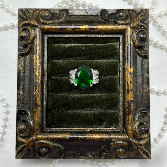 Rhodium plated vintage deadstock ring with large green center stone surrounded by clear cubic zirconia stones.