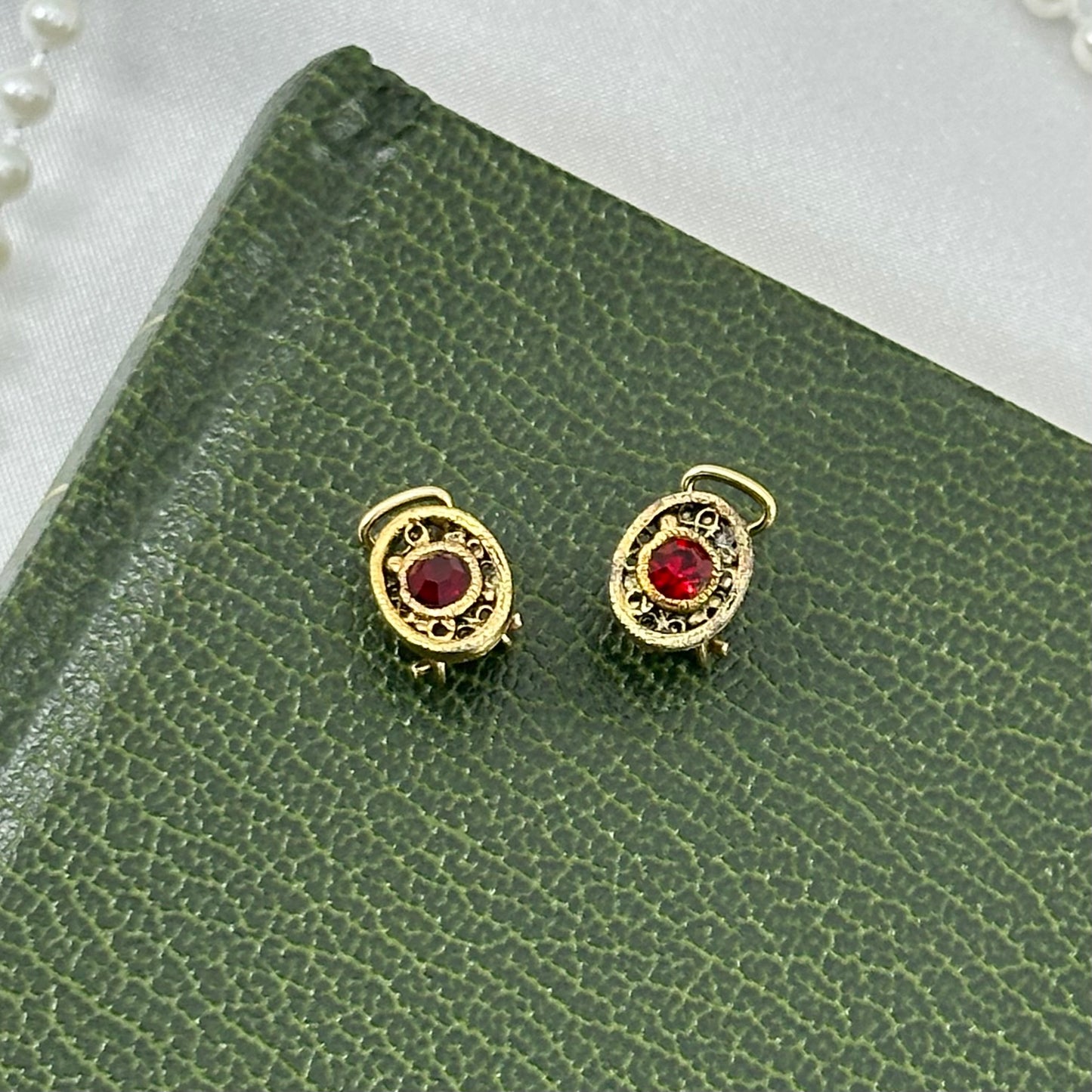 Dainty vintage gold tone oval clip on earrings with red stones.