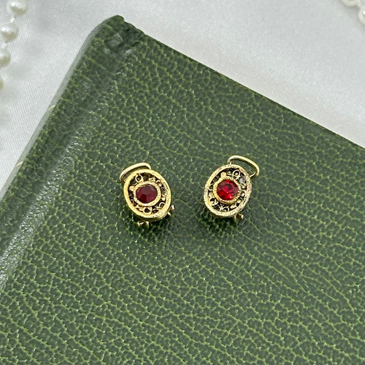 Dainty vintage gold tone oval clip on earrings with red stones.