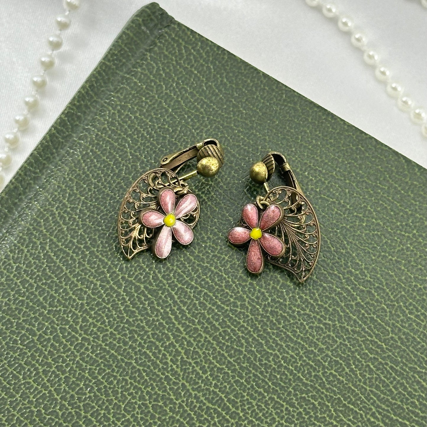 Vintage bronze tone clip on dangle earrings with metal leaves and pink flower charms.