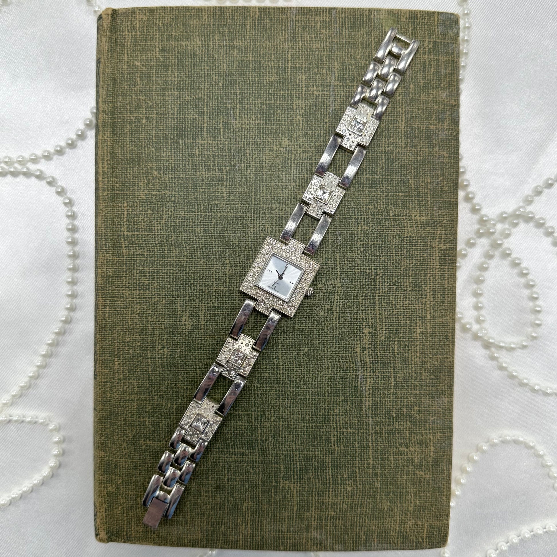 Elegant vintage silver tone watch with square dial and quartz movement.