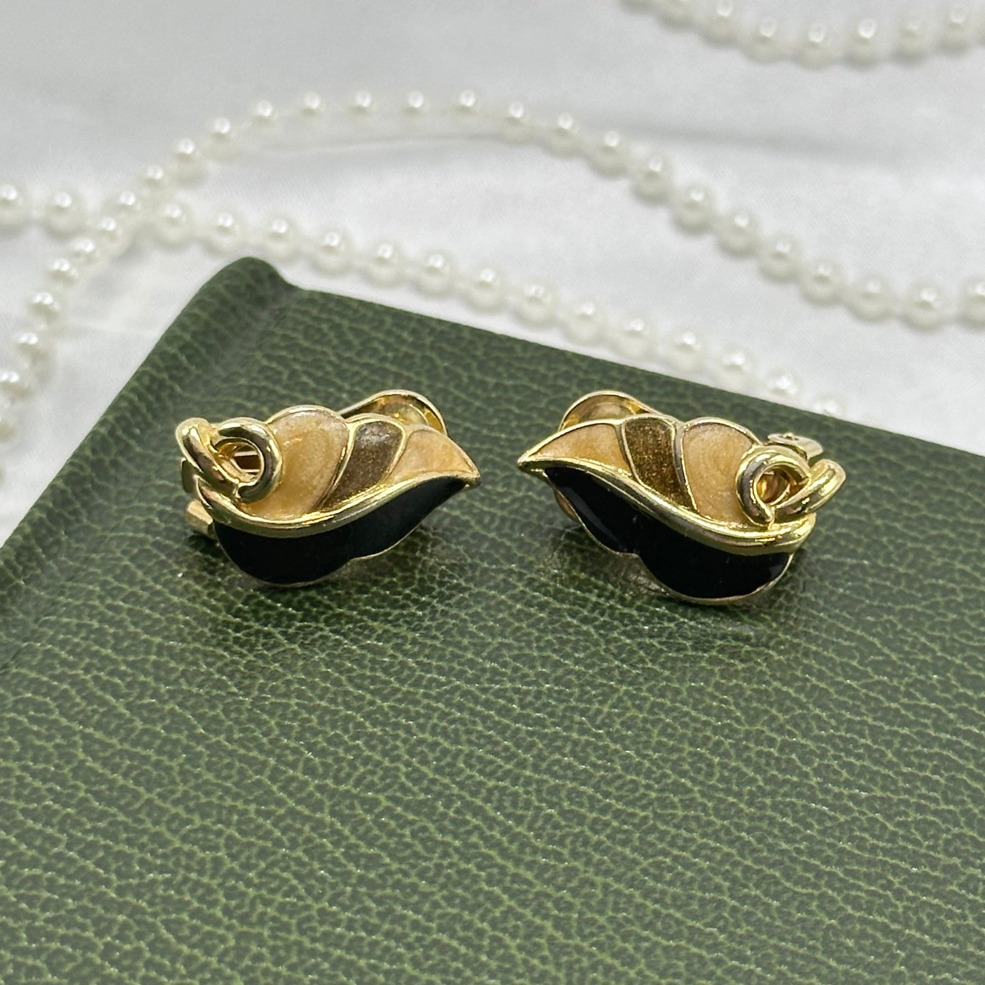 Vintage gold tone abstract leaf clip on earrings with black and tan enamel details.