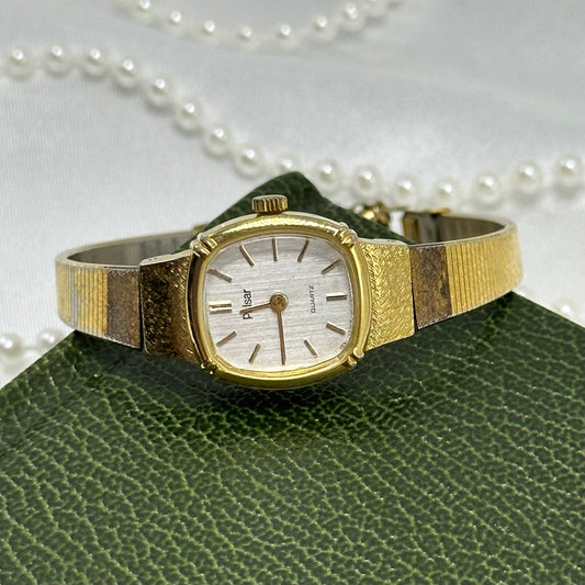 Vintage gold tone Pulsar watch with square dial and metal band.