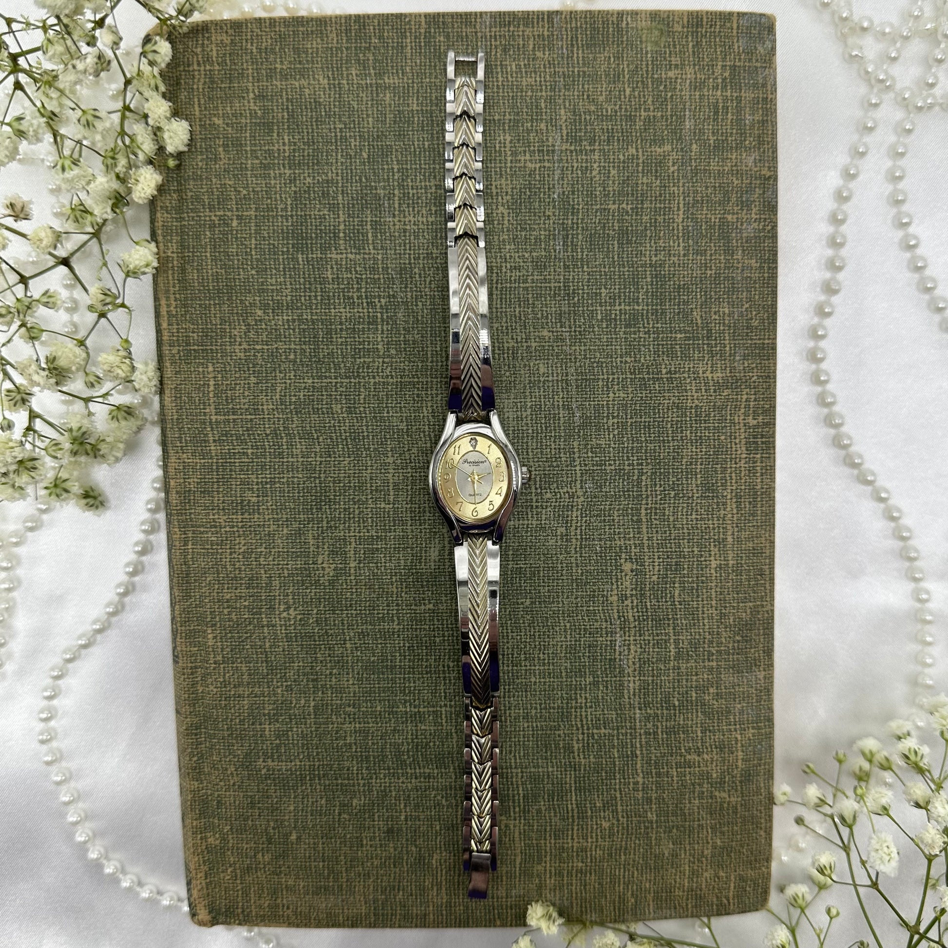 Gold and silver tone Gruen Precision watch with quartz movement and clasp band.