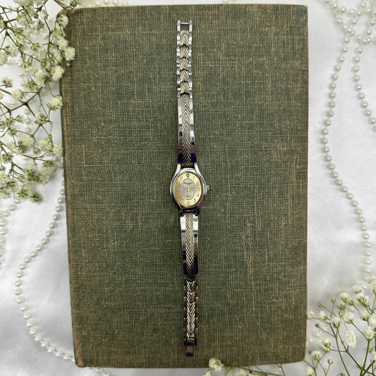 Gold and silver tone Gruen Precision watch with quartz movement and clasp band.