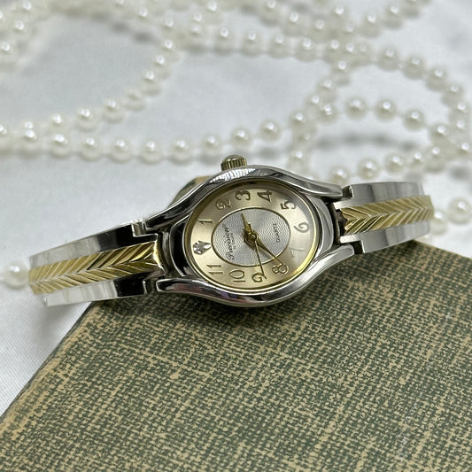 Gold and silver tone Gruen Precision watch with quartz movement and clasp band.