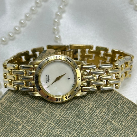 Gold tone Citizen Elegance watch with mother of pearl dial and roman numeral markers.