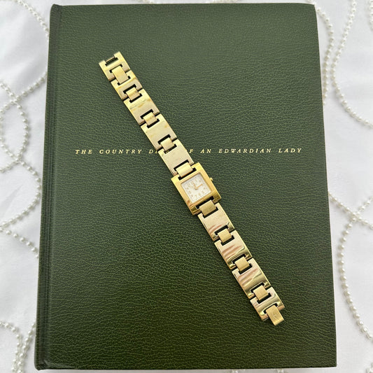 Gold tone Ecclissi watch with square dial and metal link band. Water resistant.