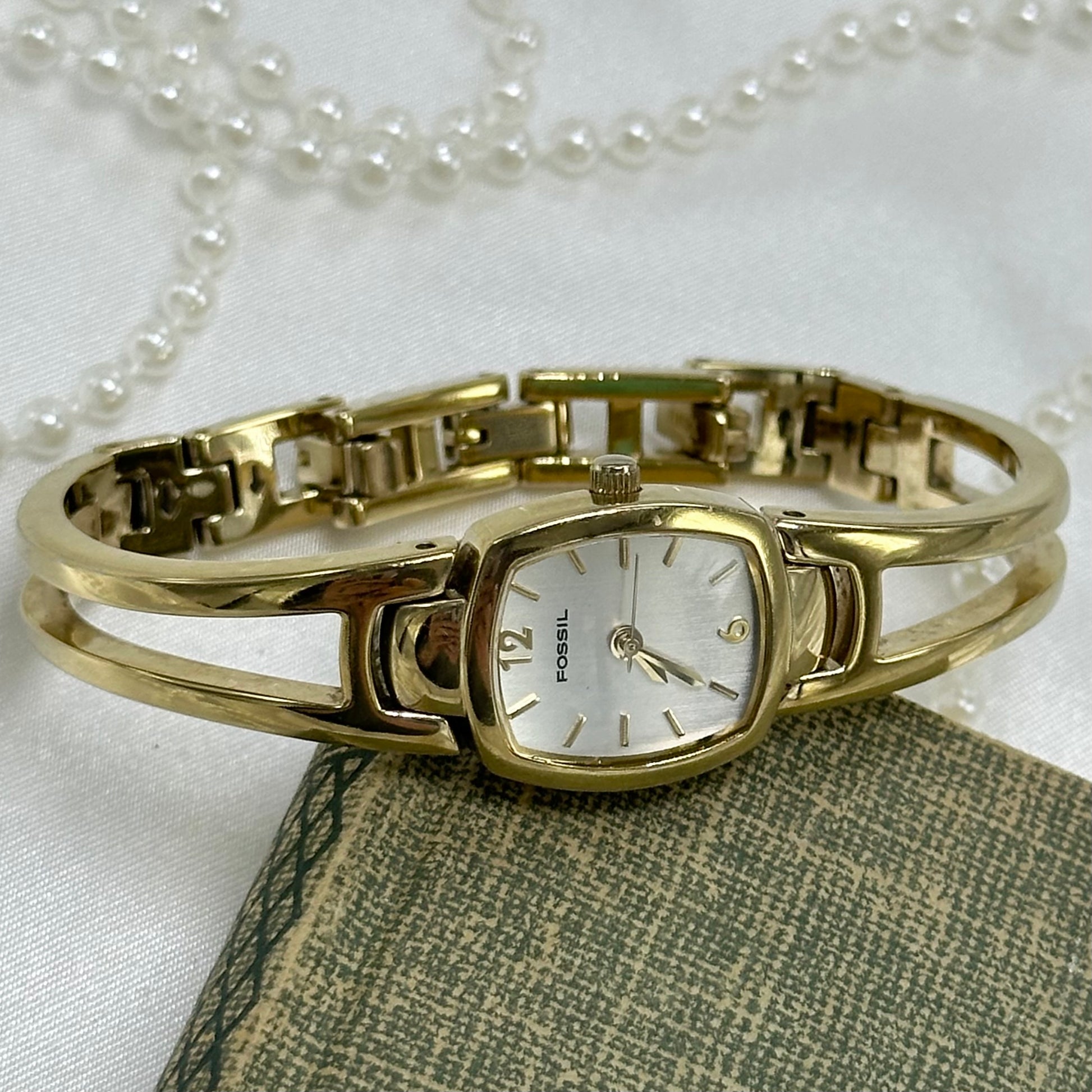 Gold tone Fossil watch with cuff band and quartz movement.