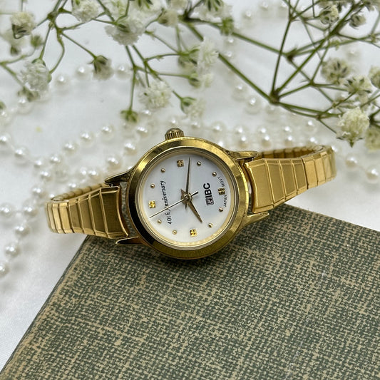 Gold tone IBC 40th Anniversary watch with stretchable band.