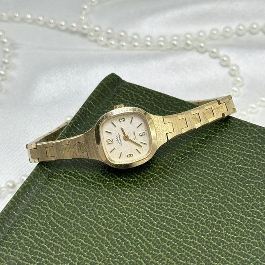Gold tone Jules Jurgensen watch with square dial dial and slender link band.