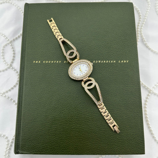 Gold tone TIME watch with diamanté oval dial and interlocking "CC" style links on the bracelet. Glass is cracked.