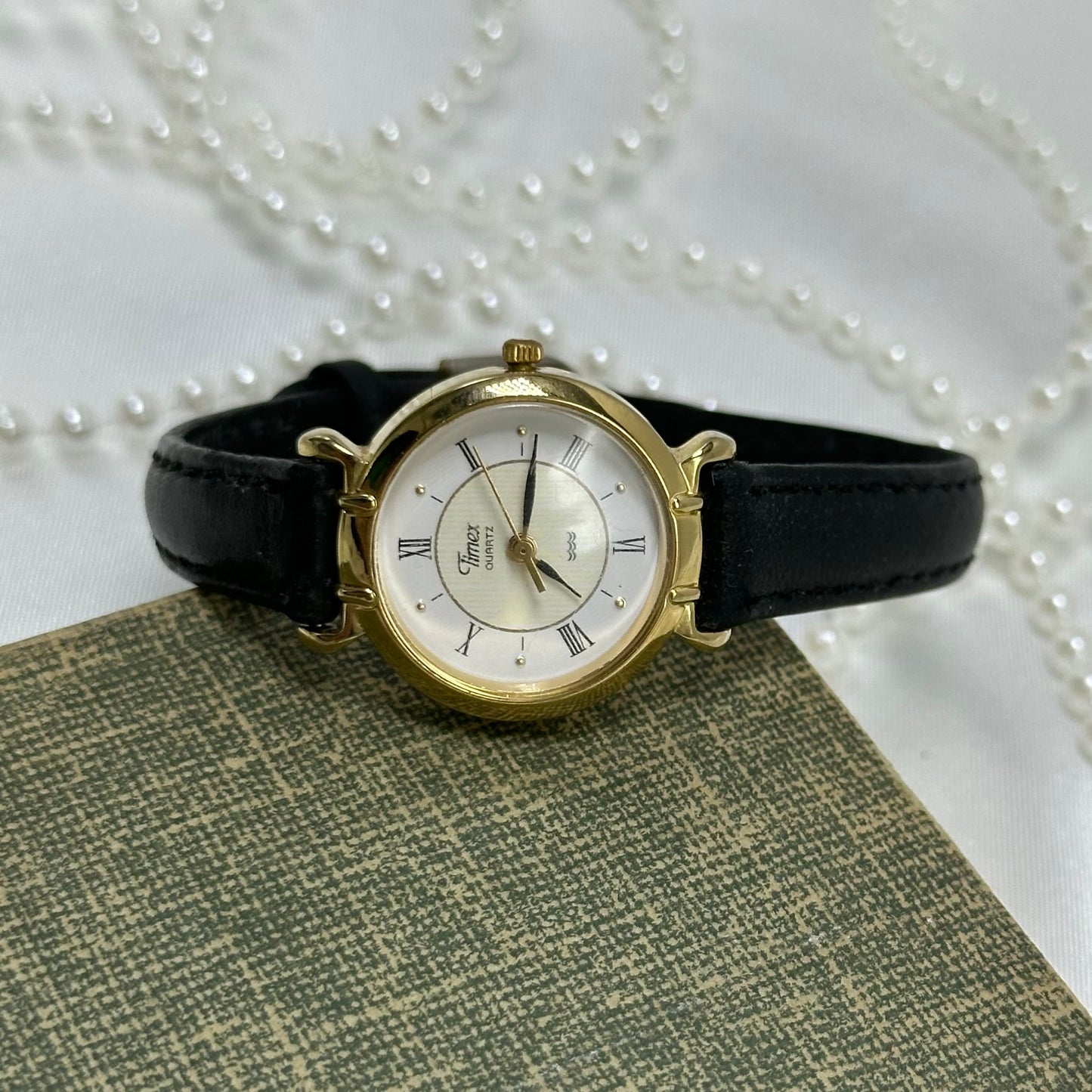 Gold tone Timex round dial watch with black leather band and quartz movement. Water resistant.